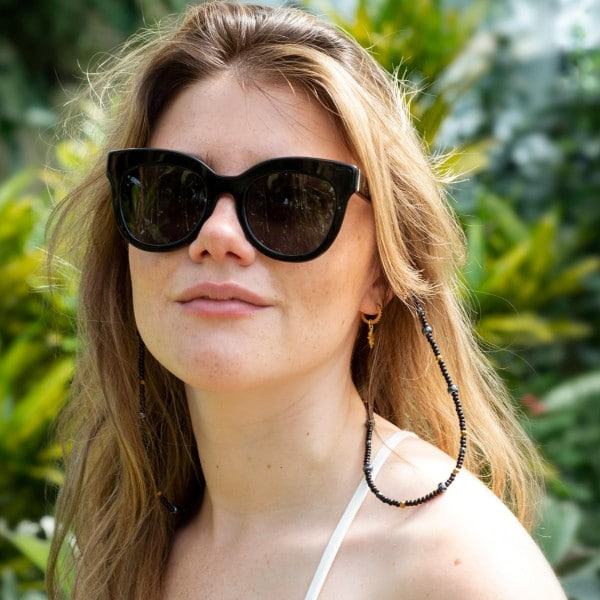 Woman wearing sustainable Pala Mzuri sunglasses with Yala black glass beaded sunglasses chain