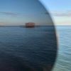 view of pier through grey eco sunglasses lens