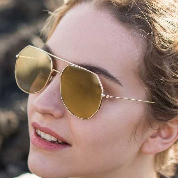 woman wearing angular aviator sunglasses with a gold lens