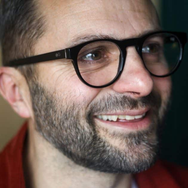 Vintage round glasses frame in black being worn by a man. Details show a keyhole bridge.