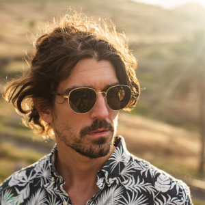 Man wearing gold round metal sunglasses with green tinted high quality polarised lenses